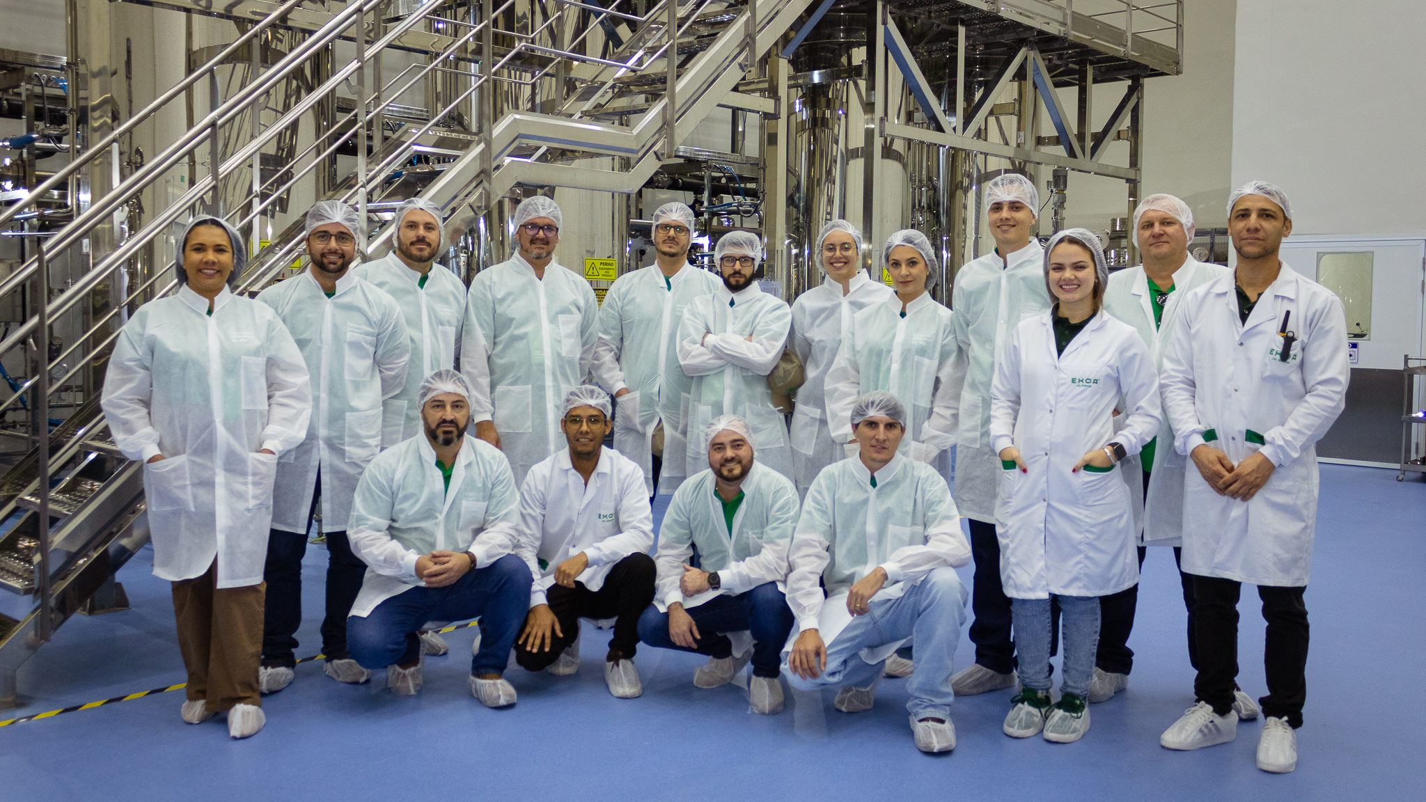 Equipe e visitantes em area industrial da EKOA usando vestimentas de seguranca